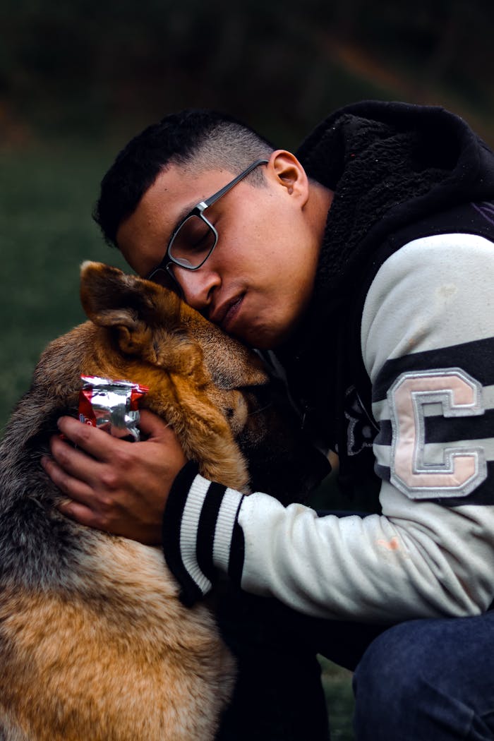 A man affectionately embraces his German Shepherd outdoors, showcasing a deep bond.